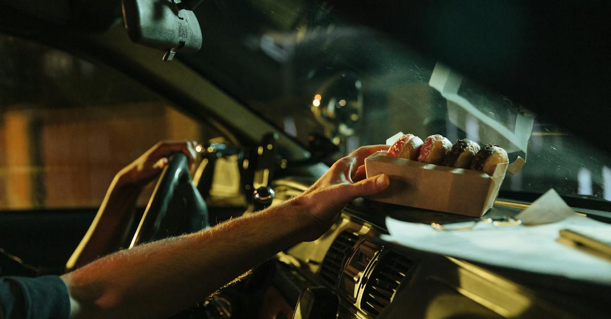 a-person-placing-a-box-of-donuts-on-the-car-dashboard