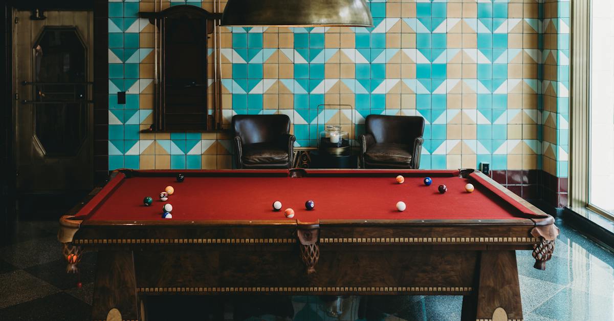 a-pool-table-in-a-room-with-a-blue-and-green-patterned-wallpaper