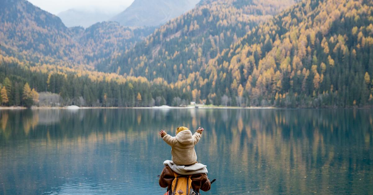 back-view-of-a-person-carrying-a-baby-near-the-placid-lake-scenery-1