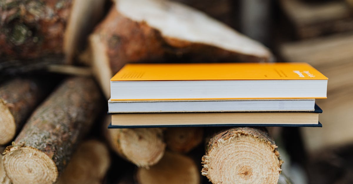 books-placed-on-edge-of-freshly-prepared-woodpile-in-backyard-of-countryside-house