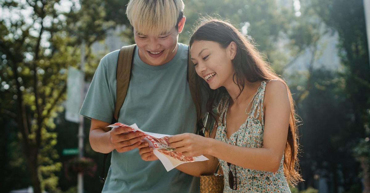 cheerful-multiracial-couple-of-tourists-watching-map-in-city