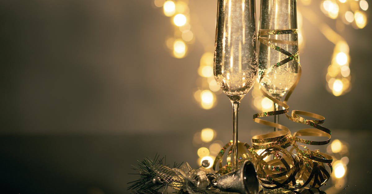 close-up-of-two-flute-glasses-filled-with-sparkling-wine-wuth-ribbons-and-christmas-decor