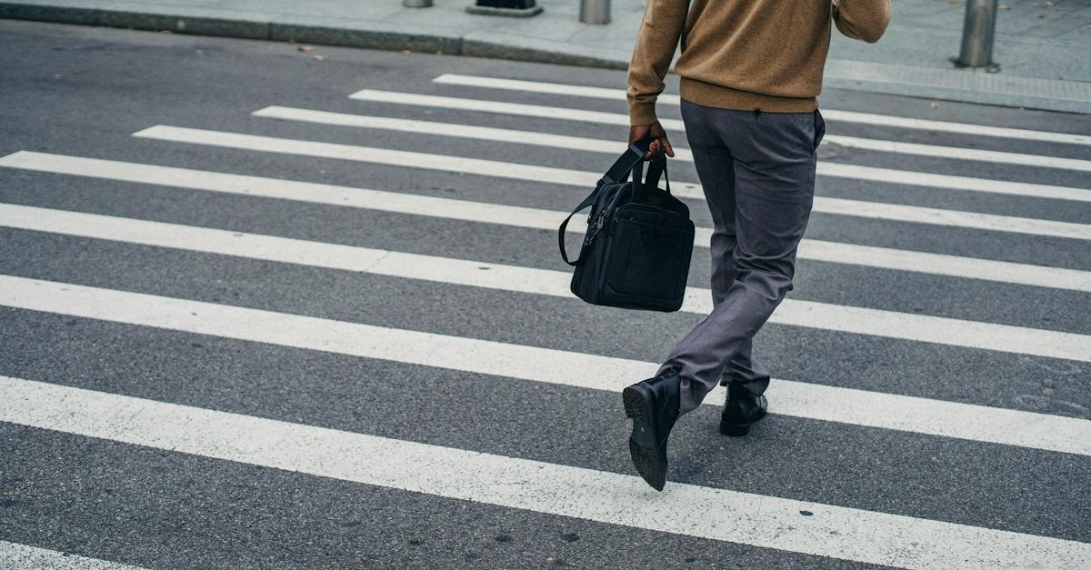 crop-back-view-of-black-male-pedestrian-with-bag-on-crosswalk-in-city-center