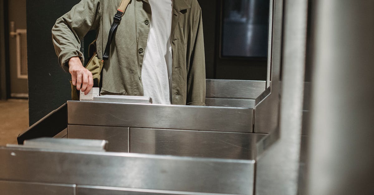 crop-unrecognizable-male-passenger-in-casual-clothes-with-backpack-inserting-ticket-in-entrance-mach-1