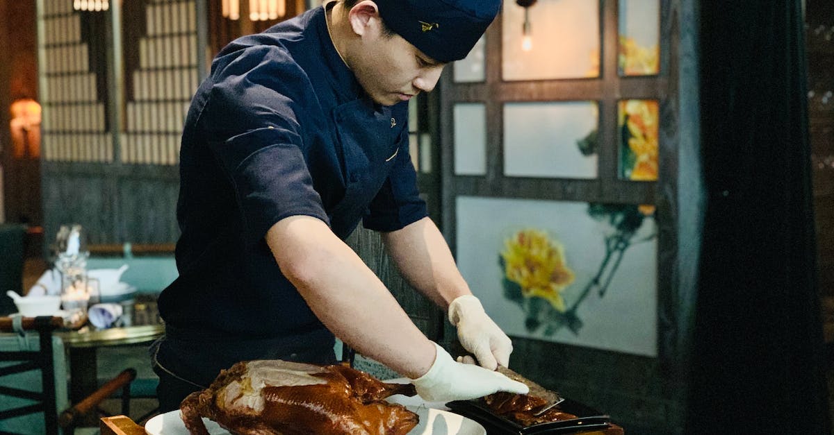 ethnic-male-cook-cutting-roasted-duck