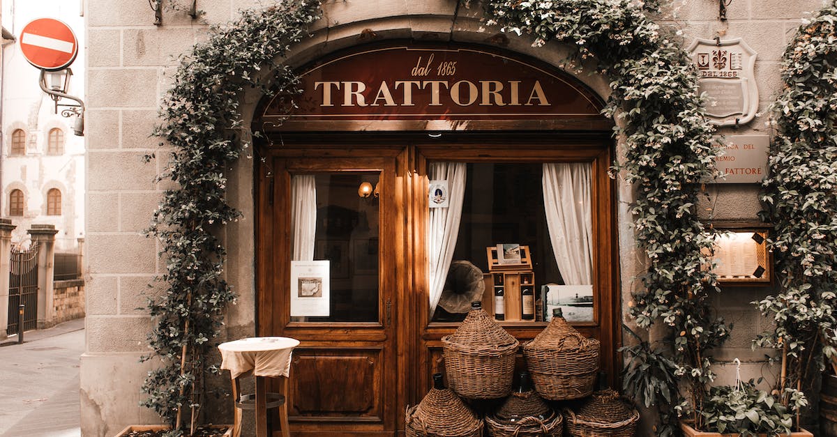 exterior-of-cozy-italian-restaurant-with-wooden-door-and-entrance-decorated-with-plants-1
