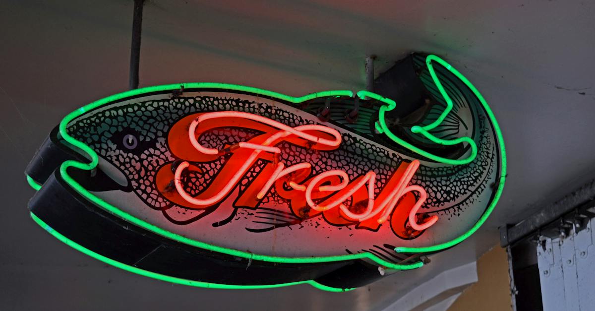 from-below-of-illuminated-neon-fish-shaped-signboard-with-fresh-inscription-hanging-on-ceiling