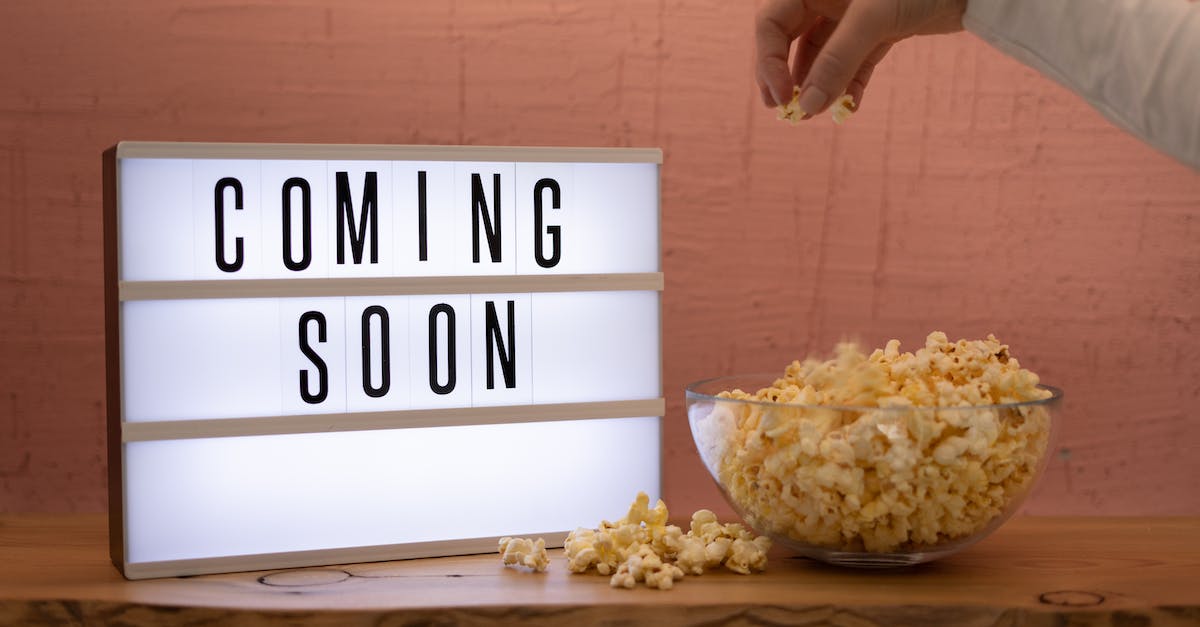 hand-picking-up-popcorn-from-bowl-set-next-to-lit-up-sign