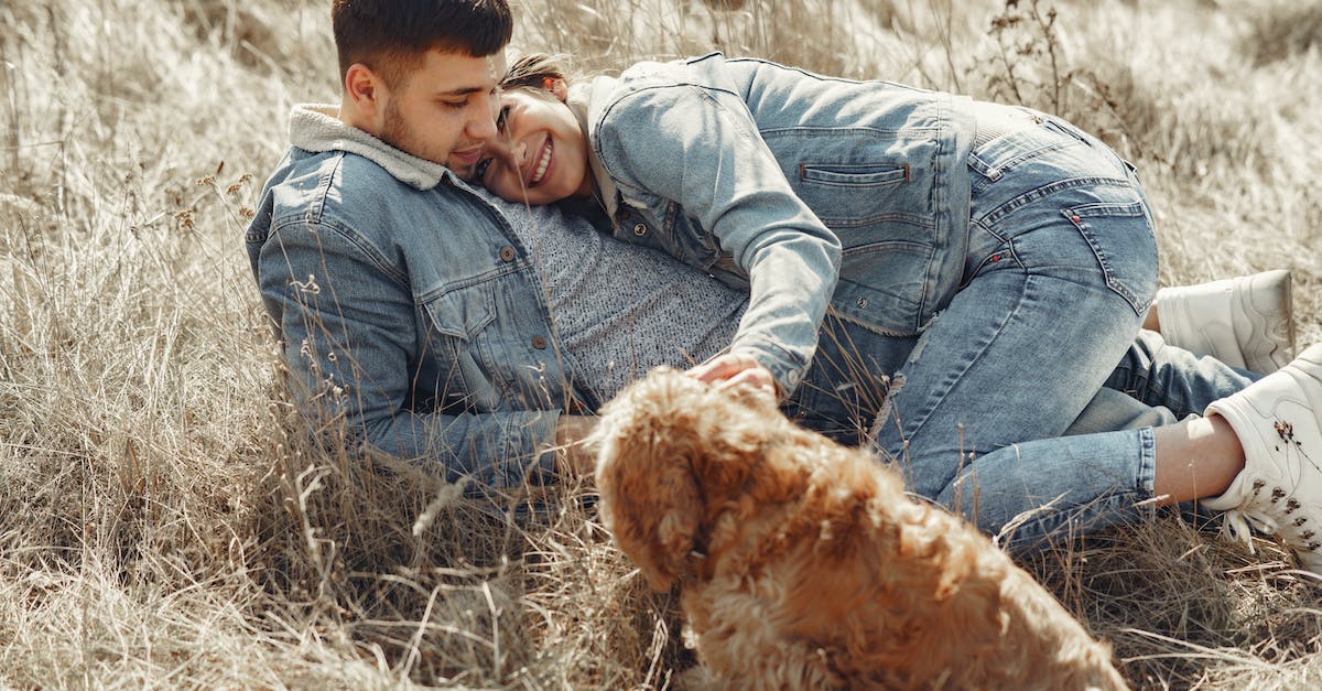 happy-couple-with-dog-lying-on-dry-grass