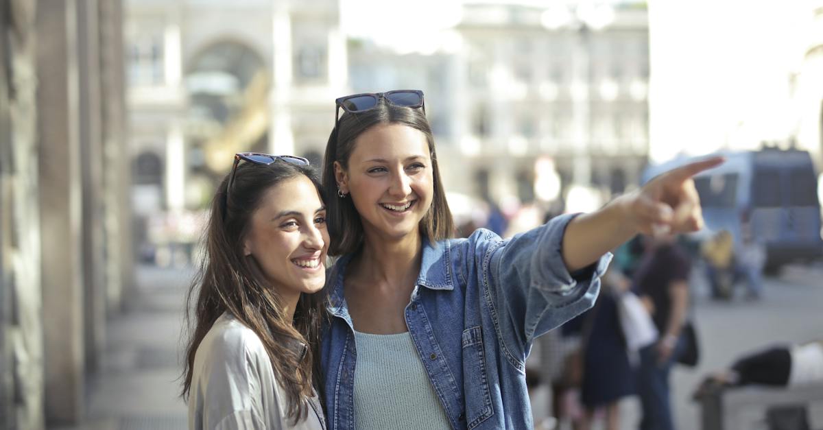 happy-young-female-friends-laughing-and-looking-away-while-woman-in-denim-shirt-pointing-to-funny-pl