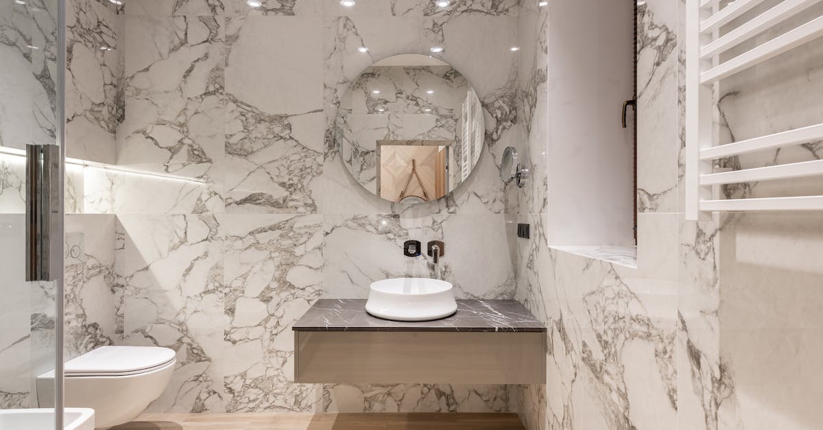 interior-of-modern-bathroom-with-round-mirror-hanging-on-marble-wall-and-white-ceramic-sink-and-toil