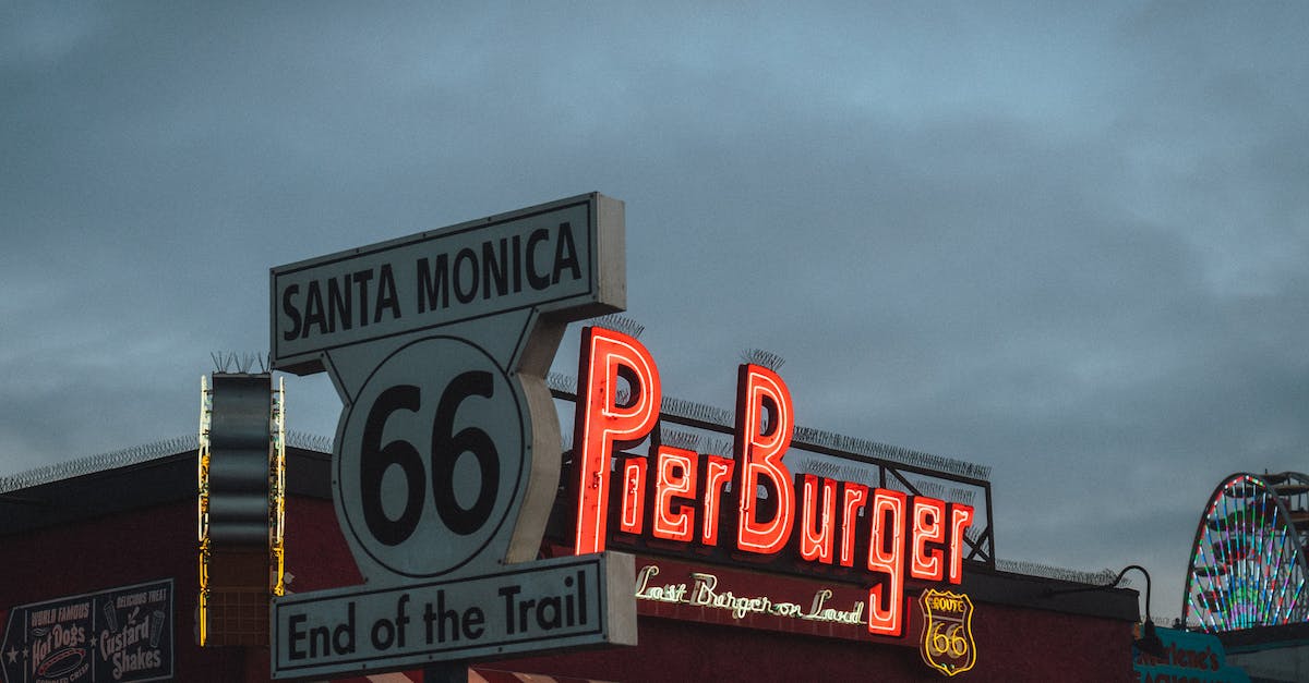 low-angle-of-road-sign-with-route-66-end-of-the-trail-inscription-located-near-fast-food-restaurant-1