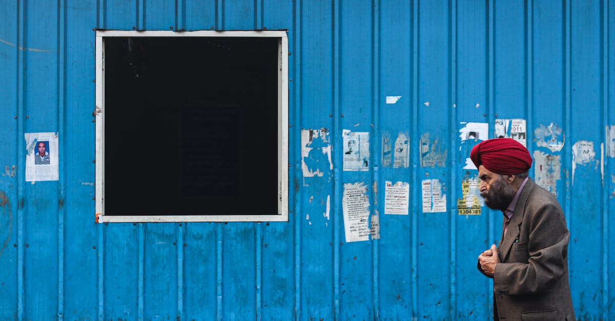 man-in-black-jacket-standing-beside-blue-wooden-door