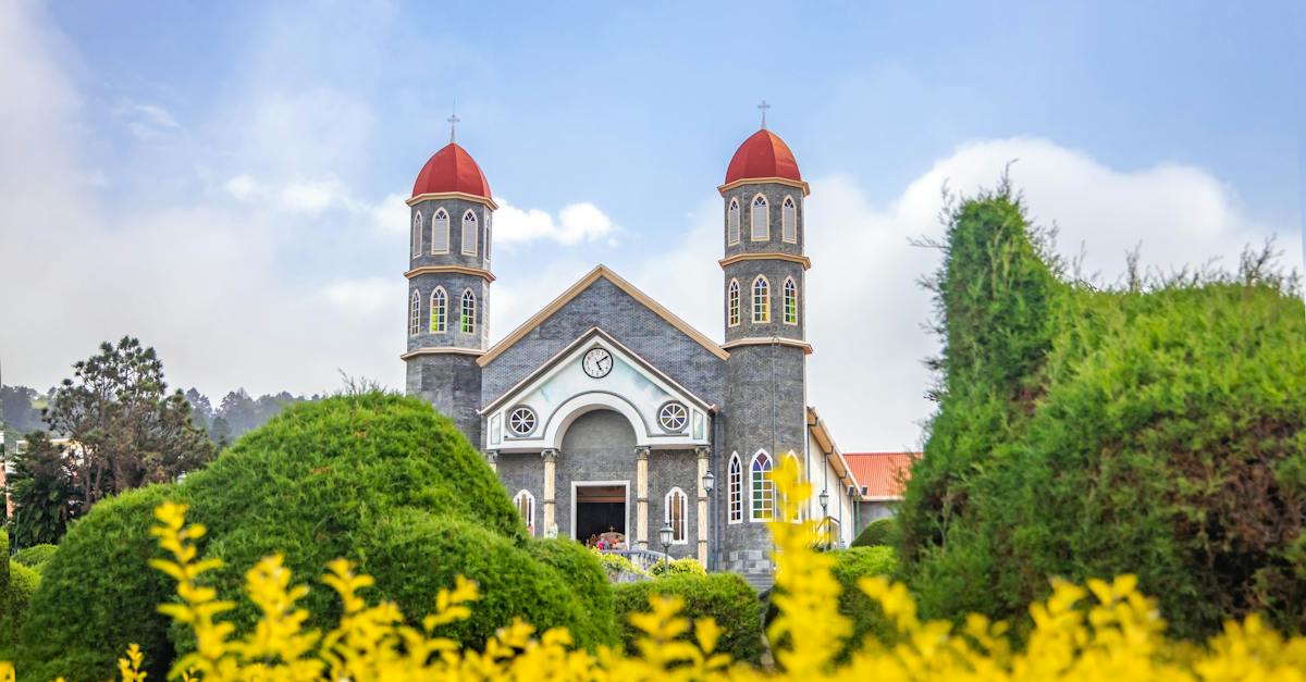 old-catholic-church-in-well-maintained-garden-against-blue-sky