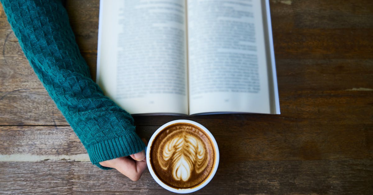 person-having-cup-of-latte-while-reading-book-1