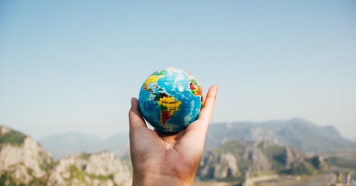 person-holding-world-globe-facing-mountain-1