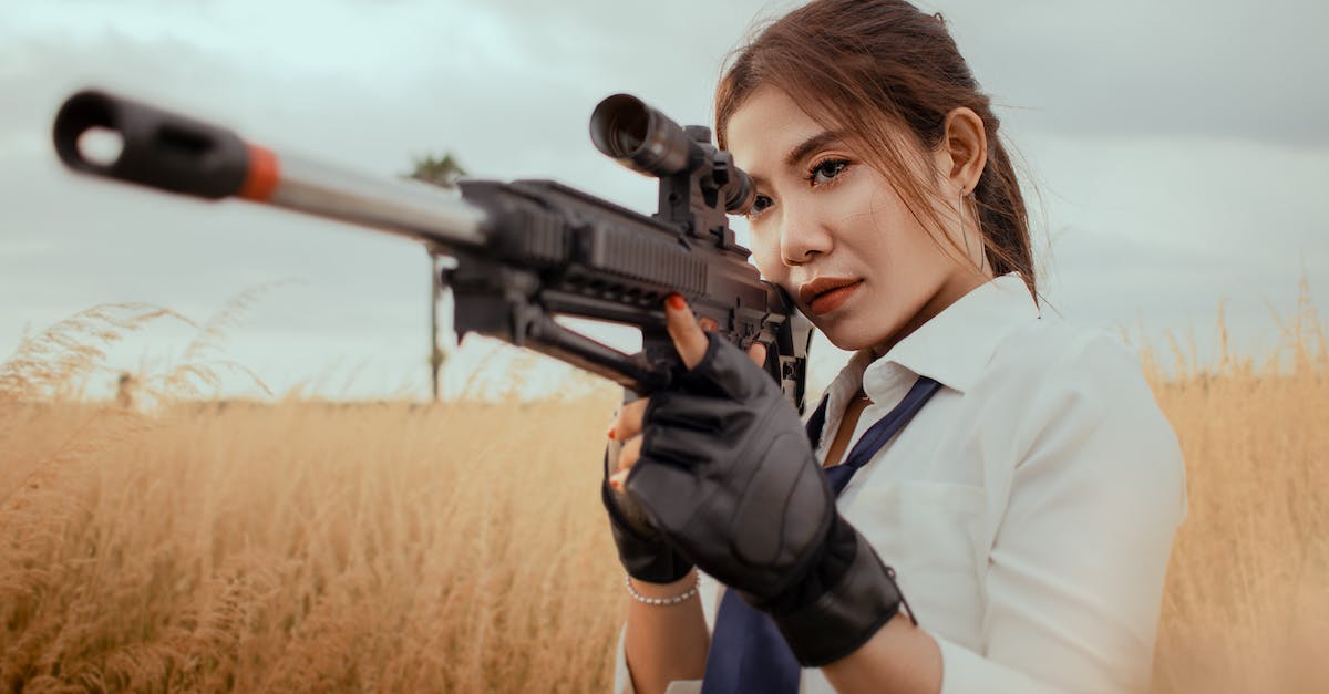 serious-asian-woman-with-rifle-on-grassy-field