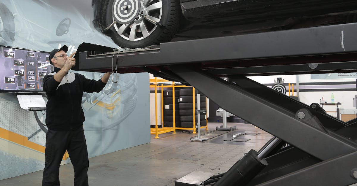 serious-mechanic-checking-car-wheels-on-lift-in-modern-car-service-garage