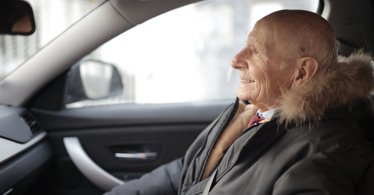 side-view-of-content-elderly-male-in-suit-and-outerwear-sitting-in-front-seat-of-contemporary-automo