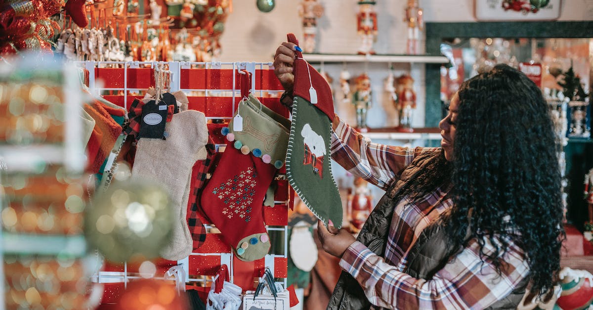 side-view-of-smiling-african-american-female-with-xmas-sock-in-shop-with-decorative-baubles-and-gift-1