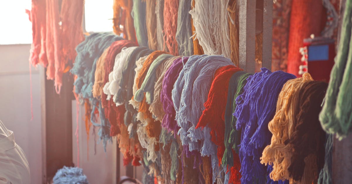 skeins-of-multicolored-threads-for-needlework-hanging-on-wooden-rack-in-light-workroom