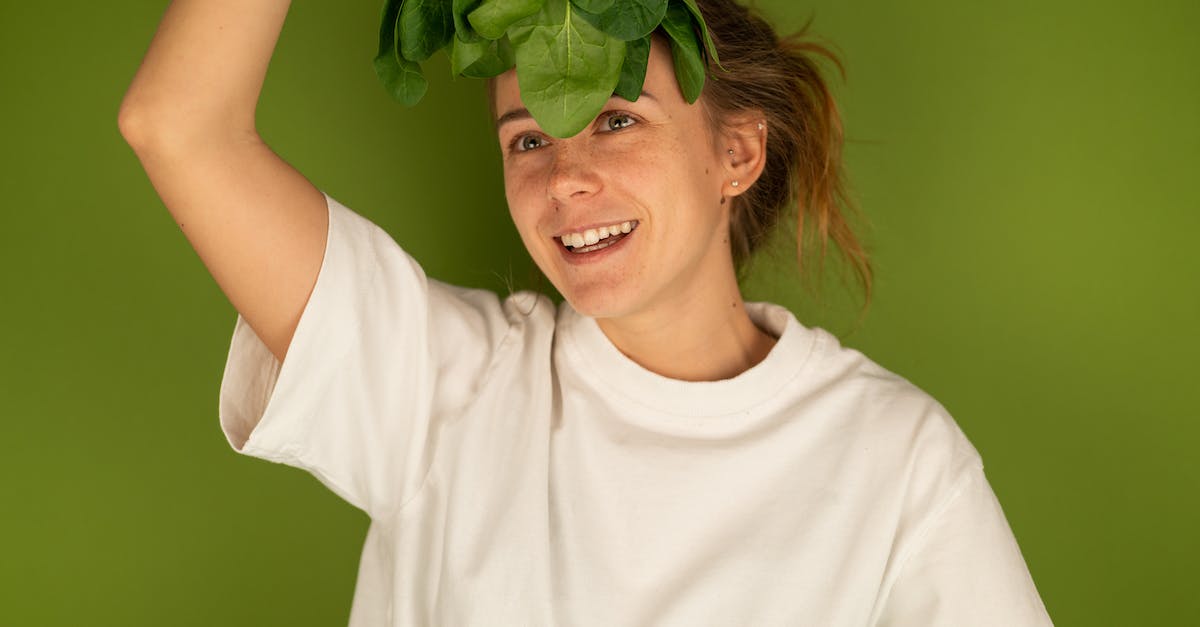 smiling-woman-with-spinach-leaves-on-green-background