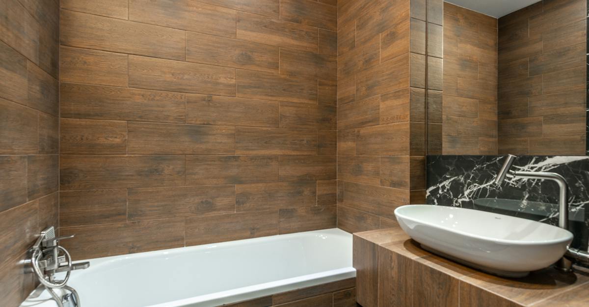stylish-interior-design-of-modern-bathroom-with-wood-like-tiles-equipped-with-white-bathtub-and-sink