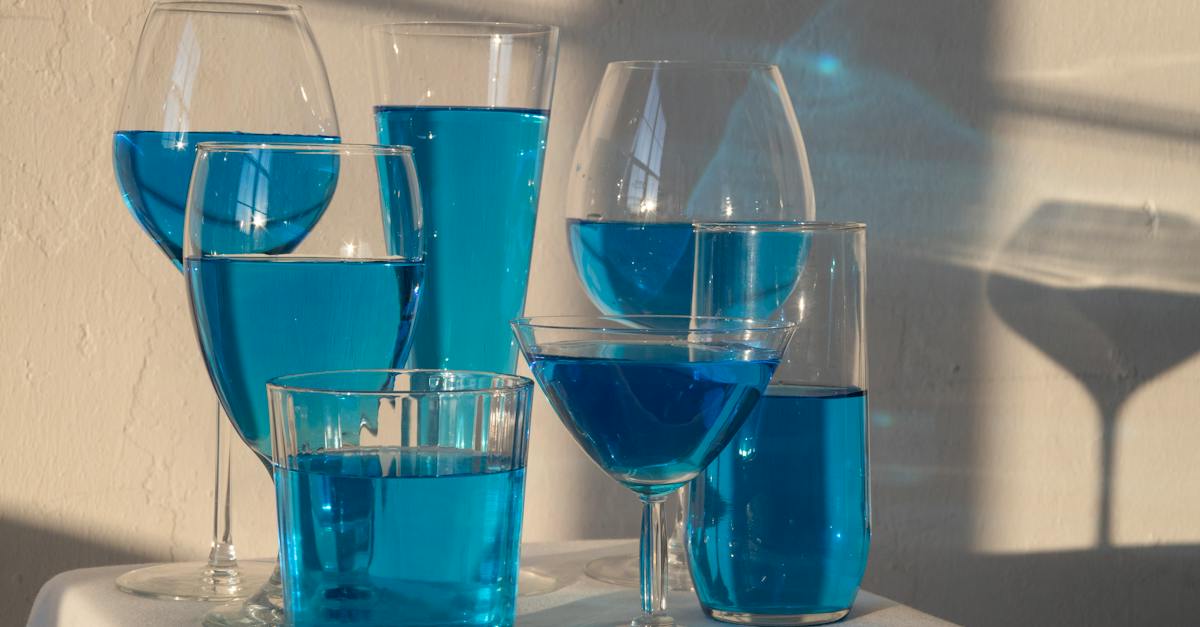 transparent-glasses-filled-with-blue-alcoholic-drink-standing-on-white-tablecloth-in-sunlight