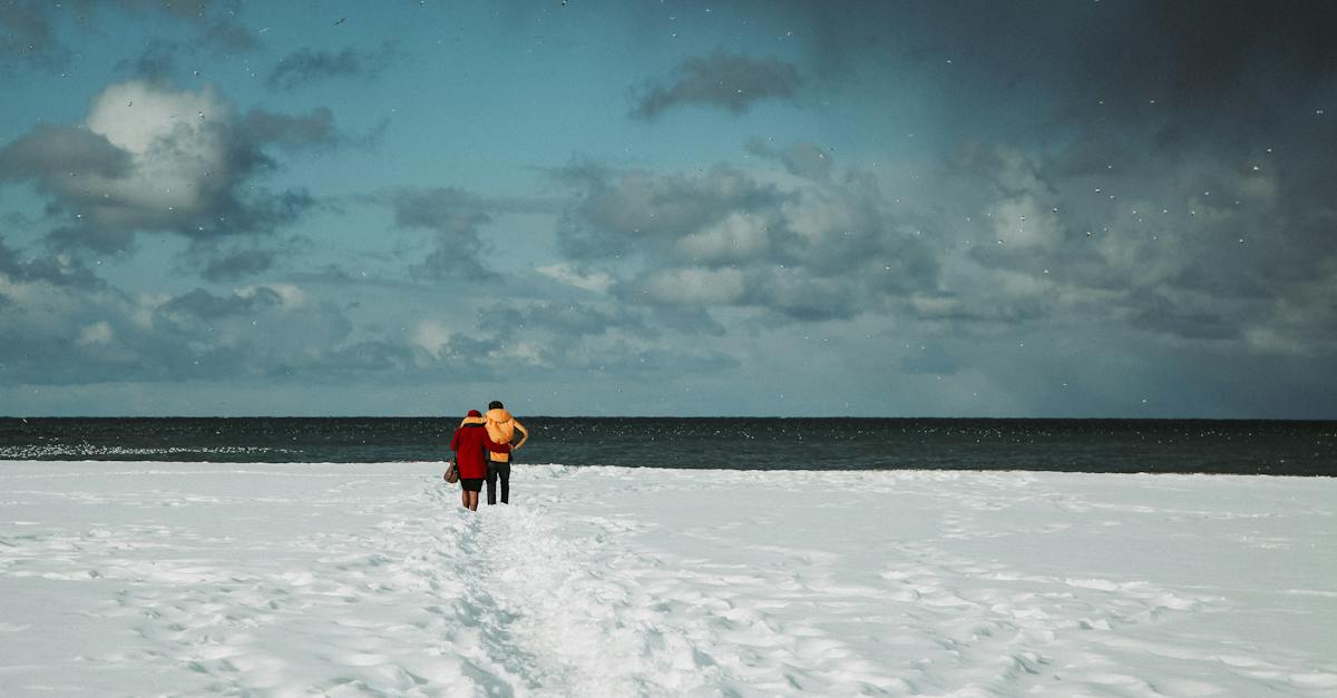 traveling-couple-standing-on-snowy-seashore