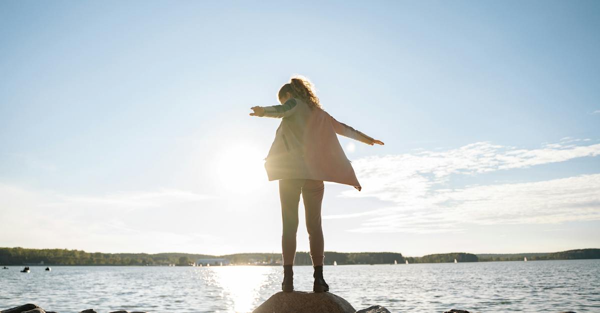 woman-in-brown-coat-standing-on-the-rock