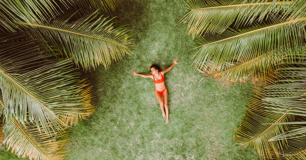 woman-lying-on-green-grass-among-palms-at-resort-2